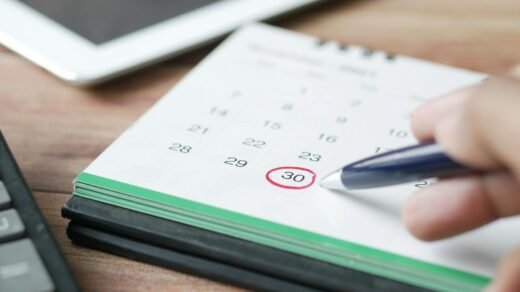 a person holding black pen pointing on calendar
