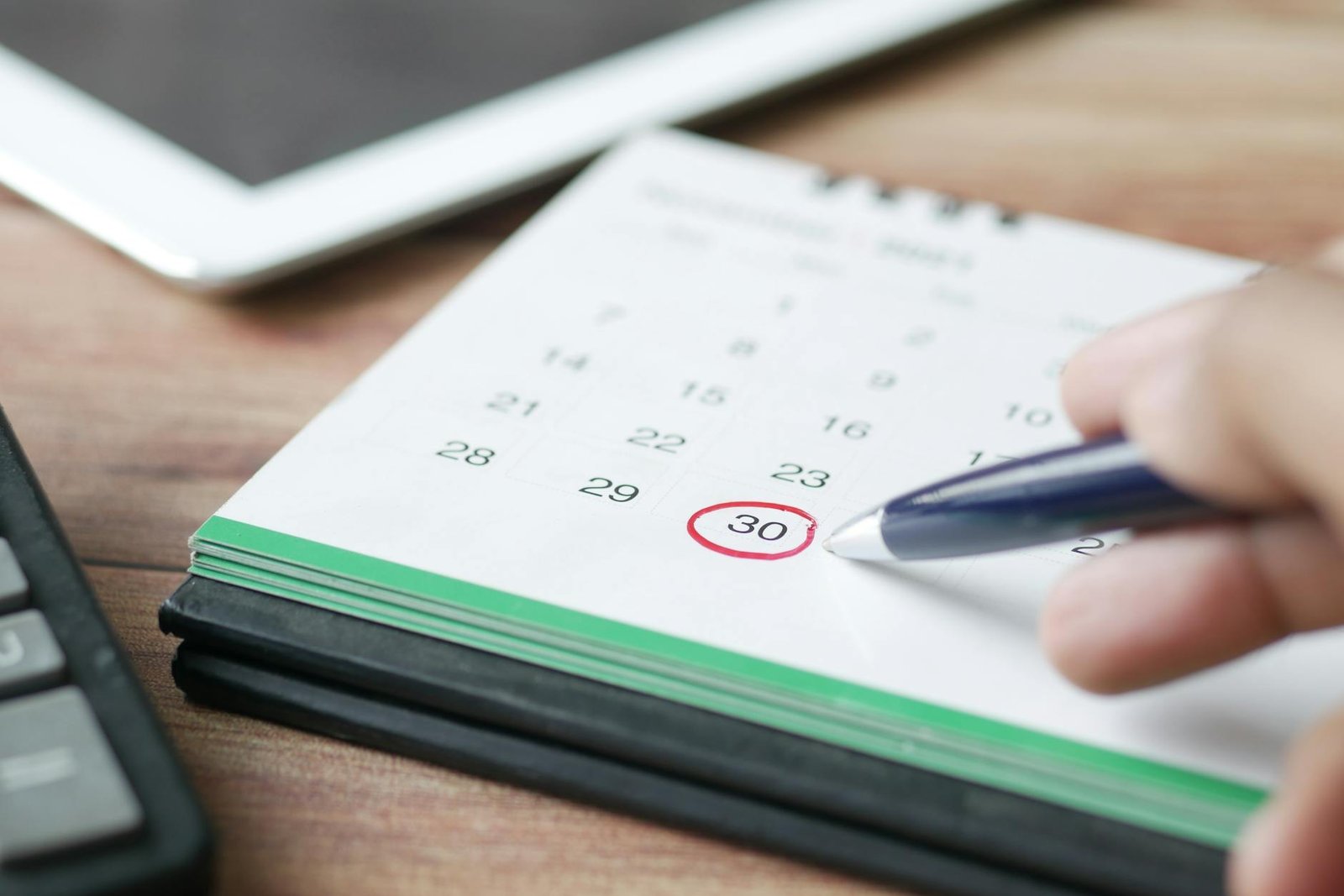 a person holding black pen pointing on calendar