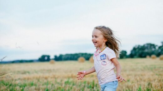 smiling girl running towards left on green field