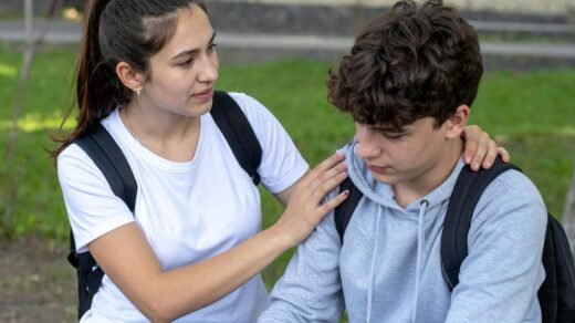 teen girl comforts sad friend outdoors at school