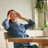 woman in blue dress touching her head