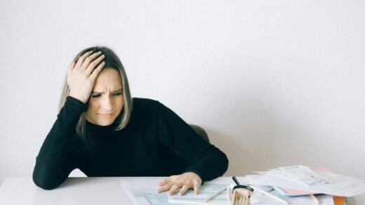 woman in black long sleeve shirt sitting with hand on her head