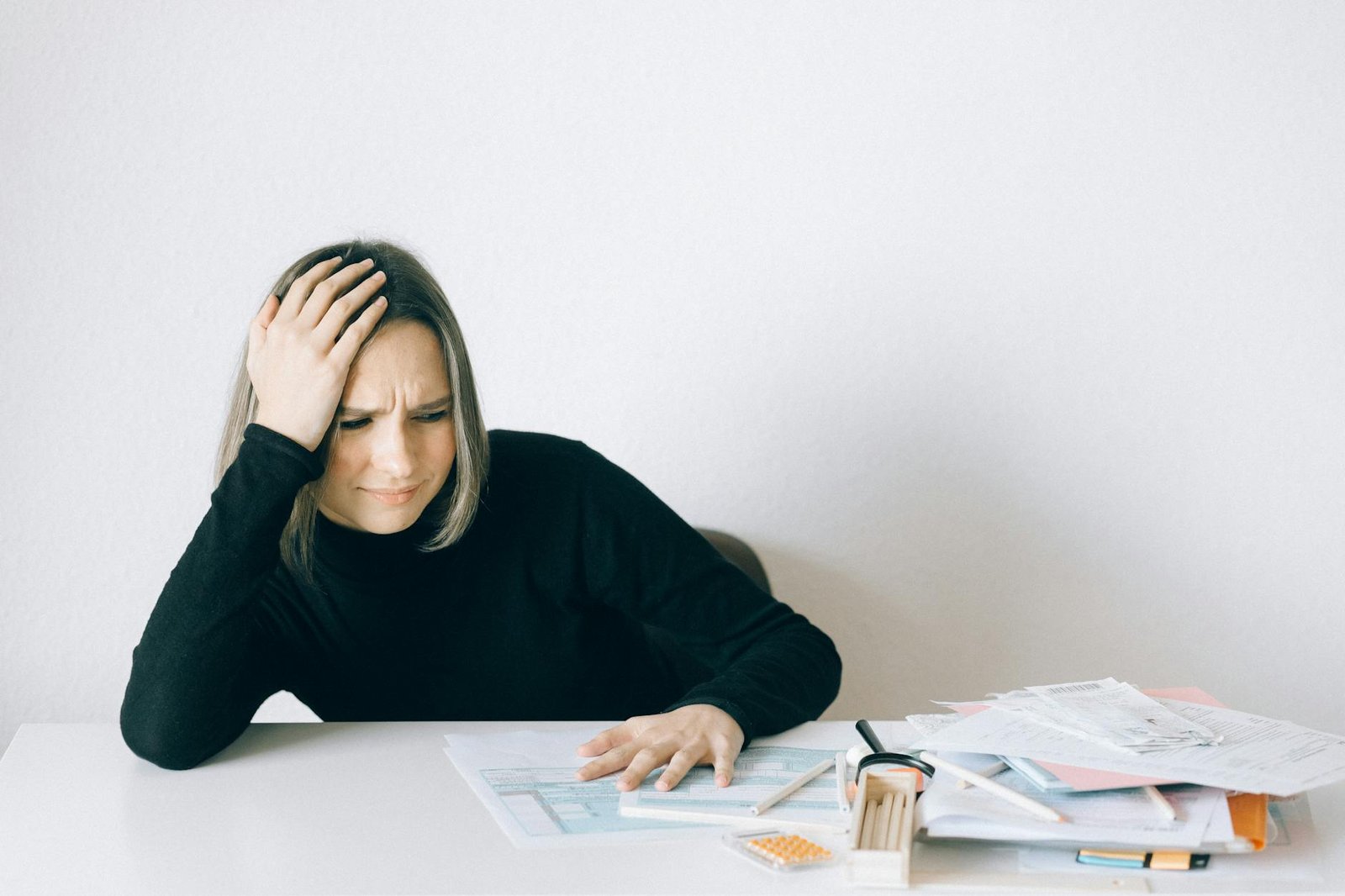 woman in black long sleeve shirt sitting with hand on her head