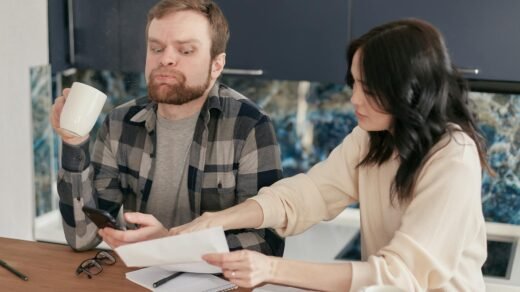 an anxious man holding a cup sitting beside a woman with a paper