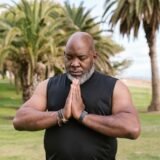 an elderly man in black tank top meditating with his eyes closed