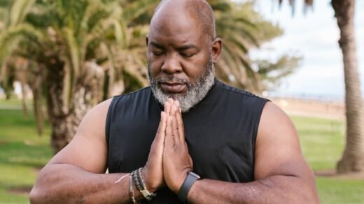 an elderly man in black tank top meditating with his eyes closed