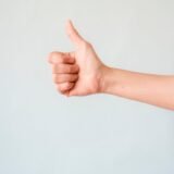 person s right hand doing thumbs up