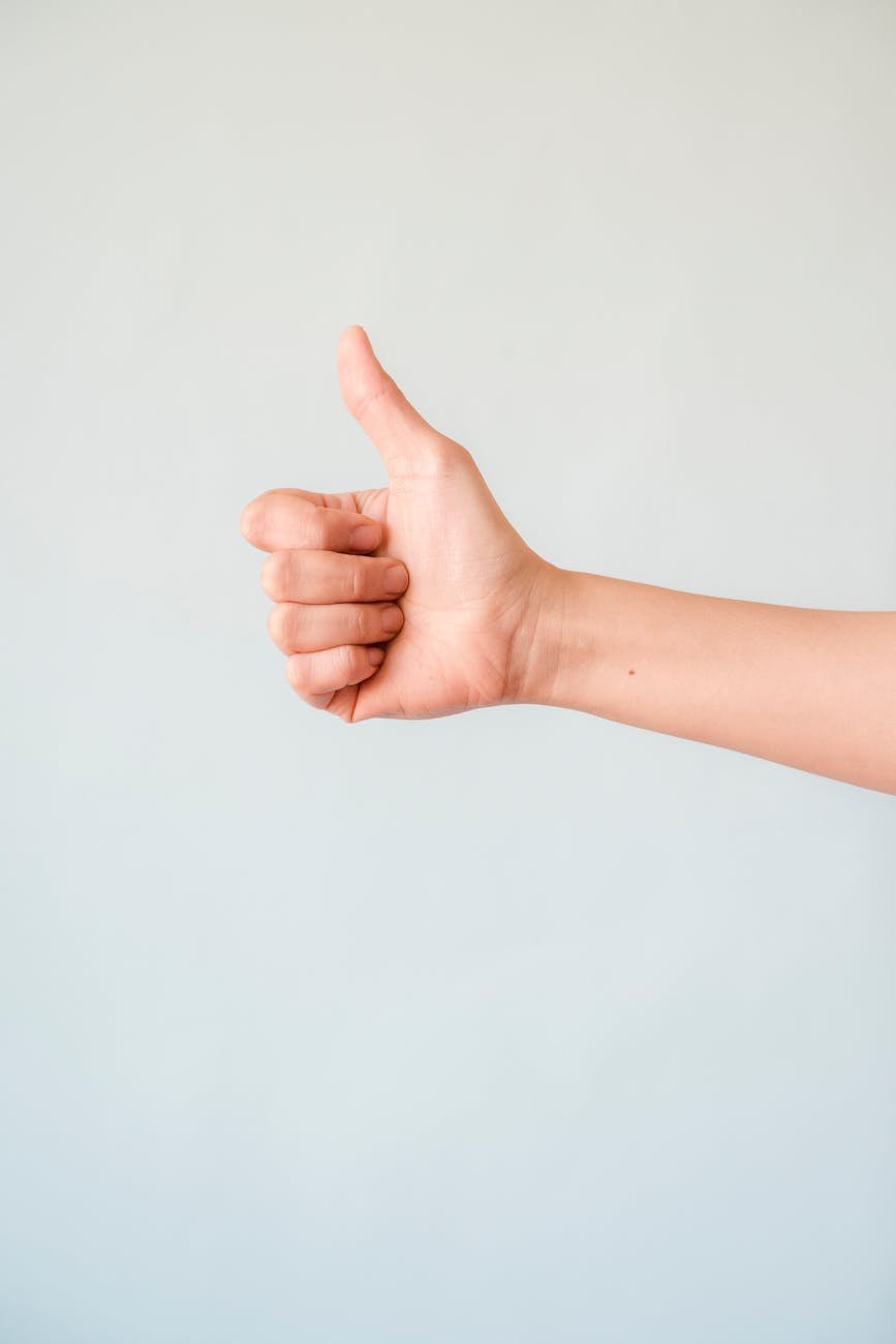 person s right hand doing thumbs up
